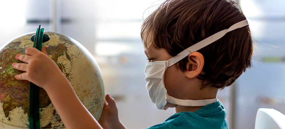 Child wearing a mask examines a Globe
