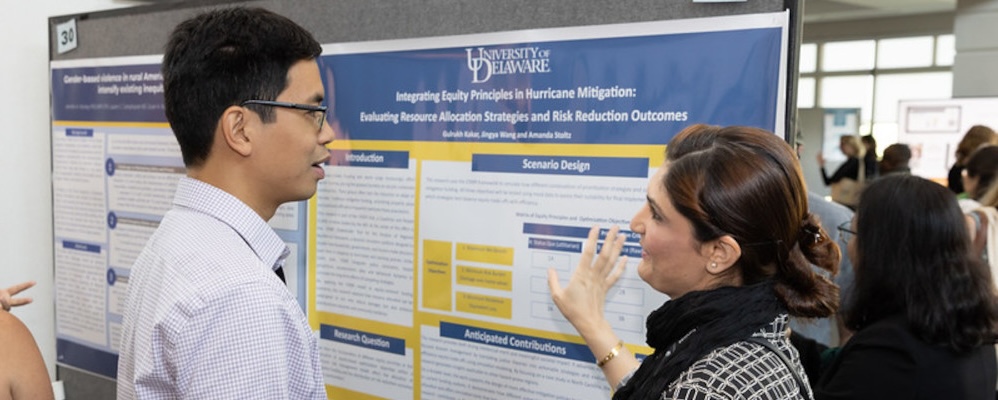 Presenter points at poster while talking with Workshop participant