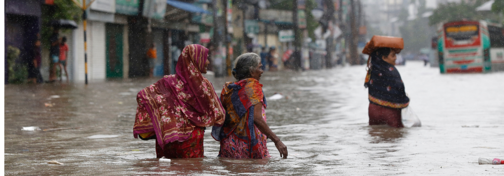 Women are walking through a flooded street after heavy monsoon rainfall in Dhaka, Bangladesh, on July 12, 2024.