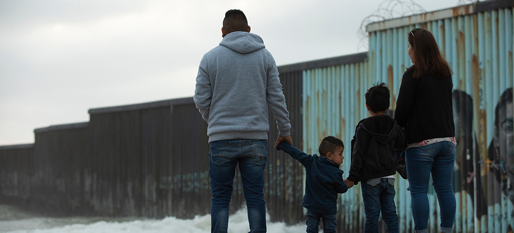 A family stands near the Mexico-U.S. border wall near Baja, California