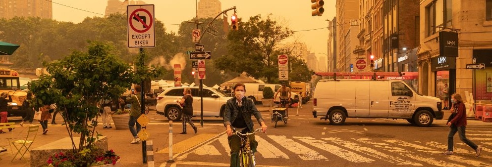 A biker in New York City wears a facial mask in a haze of wildfire smoke