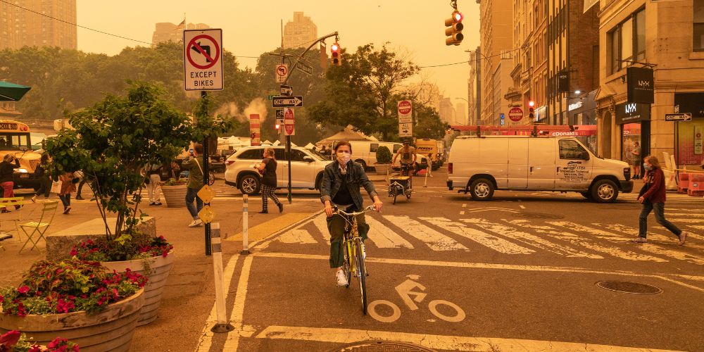 A biker in New York City wears a facial mask in a haze of wildfire smoke