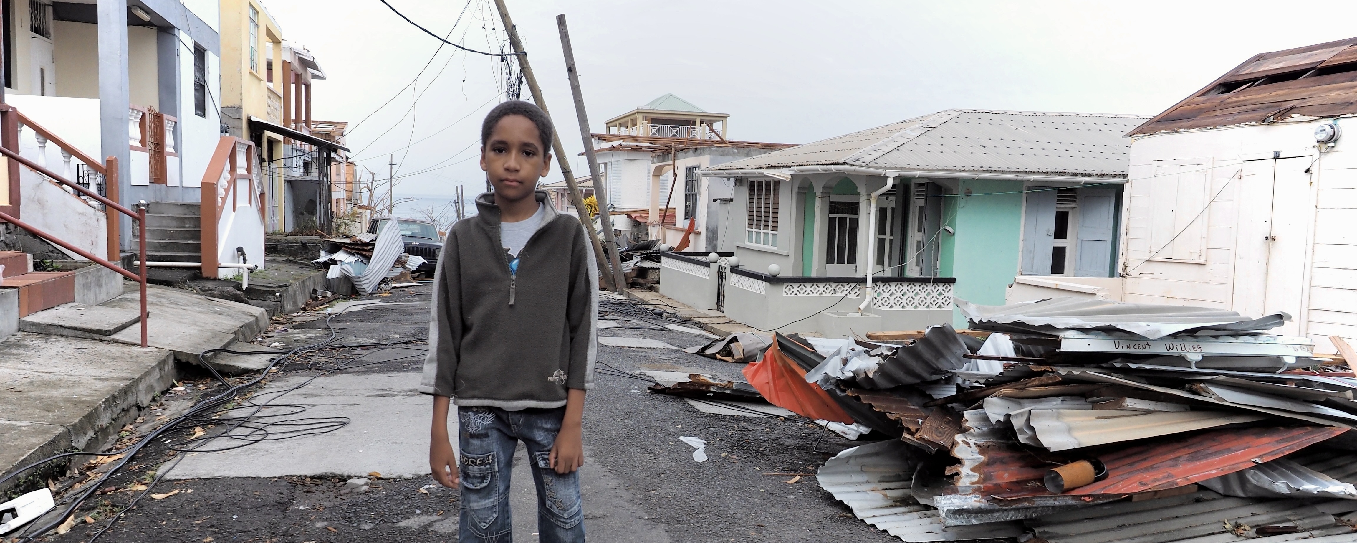 A young man stands amidst damage from Hurricane Maria